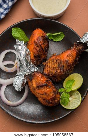 Chicken Tangri kabab or kebab - three Chicken leg pieces marinated with red sauce then grilled and served with salad. It can be served with green chutney