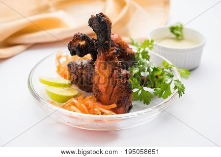 Chicken Tangri kabab or kebab - three Chicken leg pieces marinated with red sauce then grilled and served with salad. It can be served with green chutney