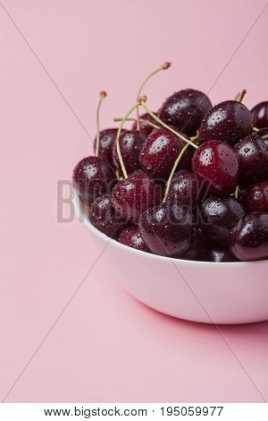 White Bowl Of Fresh Red Cherries On A Pink Background. Close-up