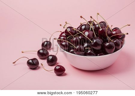 White Bowl Of Fresh Red Cherries On A Pink Background. Copy Space. Close-up