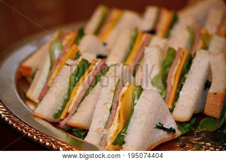 Sandwiches, sliced, arranged and served in a silver circular metal tray