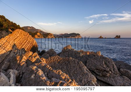 Sunset in Montenegro on the sea, Petrovac, red cliff, clouds, islands