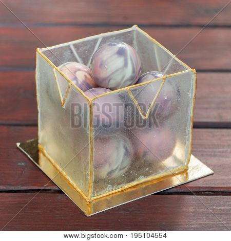 An unusual cake in chocolate balls and caramel cube from isomalt. Each bowl contains a filling of walnut mushrooms, chocolate brownies, almond praline and strawberry marmalade.