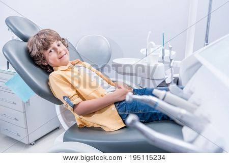 Little Smiling Boy Sitting In Chair In Dentist Office