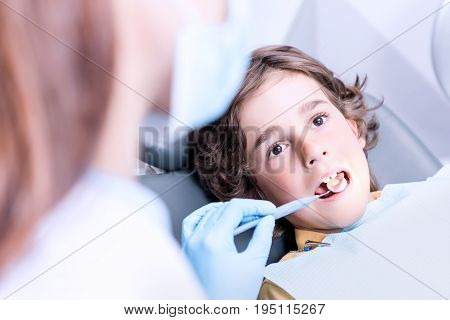 Close Up View Of Dentist Examining Teeth Of Little Boy In Dentist Office