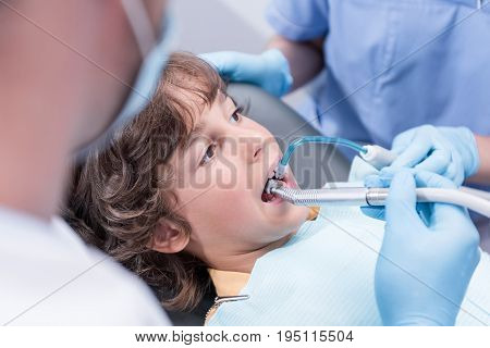 cropped shot of dentists treating teeth of boy in dental hospital