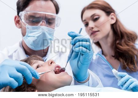 low angle view of dentists examining teeth of little boy at dentist office