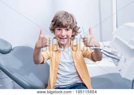Portrait Of Little Smiling Boy Showing Thumbs Up In Dental Clinic