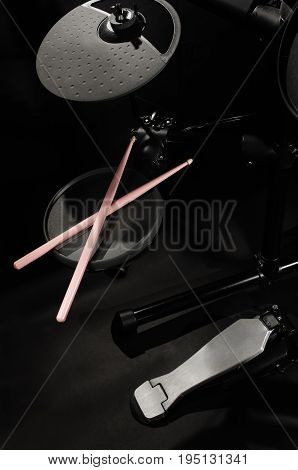 Old electronic Drum Kit and pink drumsticks on black background close-up photo.