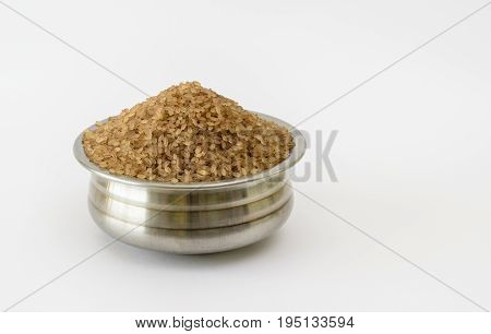 Steel container filled with parboiled Kerala Matta rice on a white background