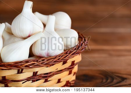 Young garlic in a wicker basket on a wooden background with empty space for text. Seasoning garlic, healthy food concept. Closeup