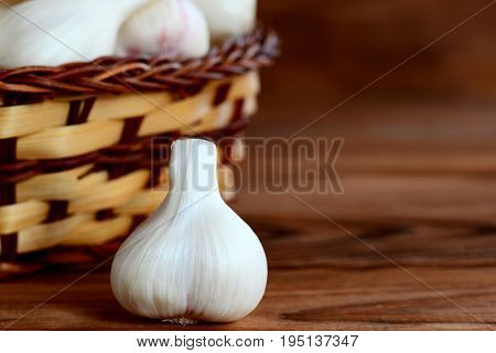Fresh young garlic in a basket on a wooden background with copy space for text. Seasoning garlic, healthy and natural food. Closeup