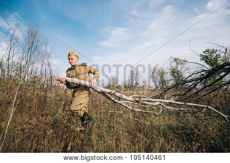 Dyatlovichi, Belarus - October 1, 2016: Man Reenactor Dressed As Russian Soviet Red Army Infantry Soldier Of World War II Equips Camp Prepares Wood For Fire At Historical Reenactment