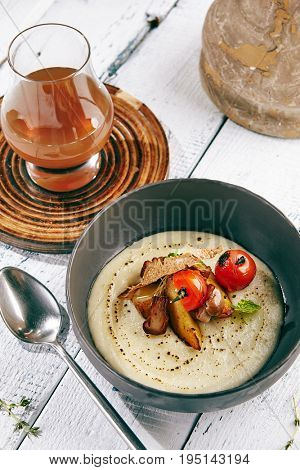 Restaurant Soup Food - Delicious Mushroom Soup with Garlic and Cherry Tomato. Gourmet Restaurant Soup Menu. Mushrooms Soup Garnished with Tea Broth and Garlic Mousse