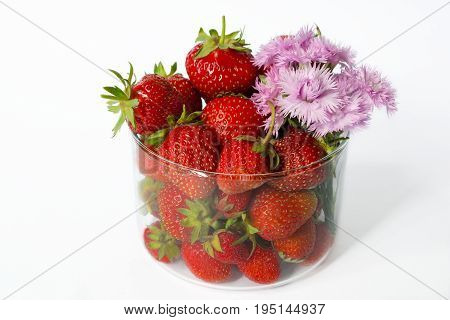 A Glass With Strawberries And Pink Flowers On A White Background. Side View