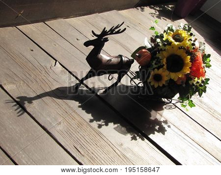 A wooden deer on a wooden floor with a flower holder