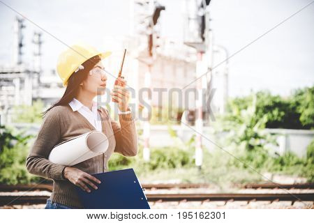 Engineers woman holding radio blueprint and report schedule for workers security control at power plant energy industry. Engineer Concept
