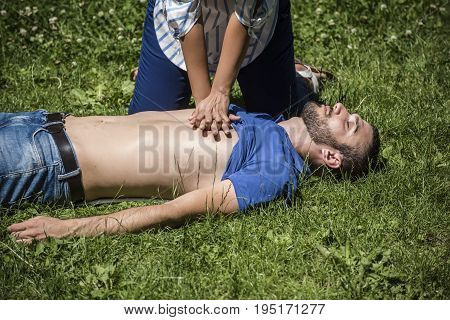 girl making cardiopulmonary resuscitation to an unconscious guy after heart attack
