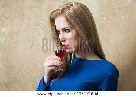 Woman In Blue Dress Drinking Red Liqueur In Glass