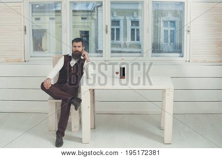Man Sitting On Chair At Table With Bottle And Glass