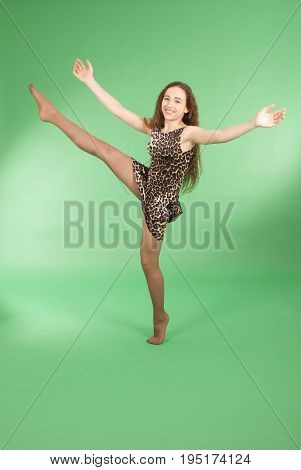 Beautiful girl dancing in trendy pantera dress and raised her leg up. Isolated on green