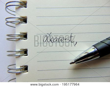 Writing a letter on lined paper beginning with Dear / Dearest