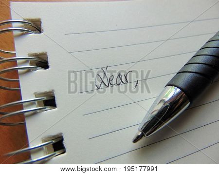 Writing a letter on lined paper beginning with Dear / Dearest
