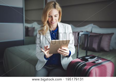 Young attractive businesswoman in hotel room holding baggage