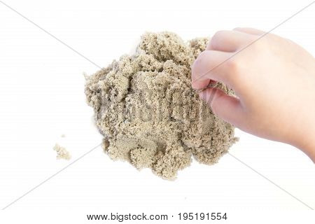 Child playing with kinetic sand. Hand of the child in the sand close up on a bright background