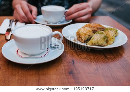 A man in a cafe eats coffee with a traditional oriental baklava dessert. Eastern food. Turkish dessert.