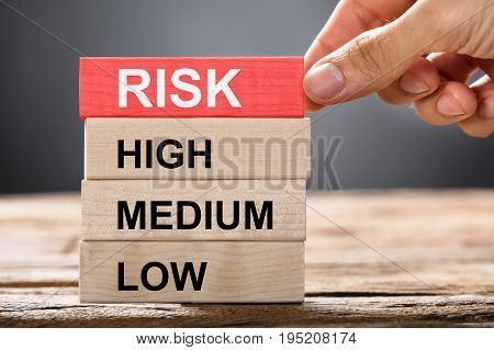 Closeup of hand building risk concept with wooden blocks on wood