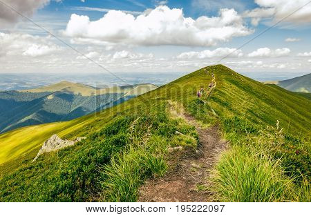 summer mountain landscape. group of tourists go by footpath uphill through the ridge to the peak