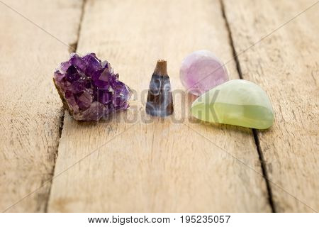 Burning Incense Cone With Amethyst And Pale Green Crystals With Wafting Smoke On Wooden Background