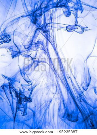 Ink swirl in a water on color background. The paint splash in the water. Soft dissemination a droplets of colored ink in water close-up. Abstract background. Explosion of color splashes acrylic ink.