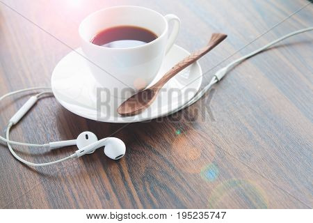 Earphones and coffee cup on wooden table Lifestyle concept