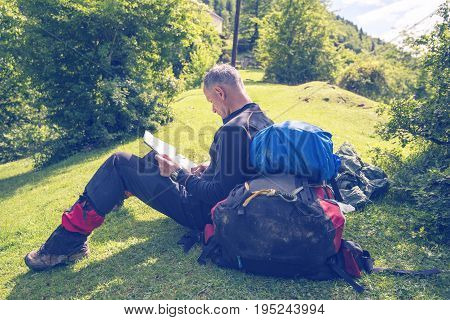 Man Traveler Sits On An Alpine Meadow With Map