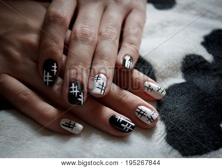 Hands of a young girl with black and white manicure