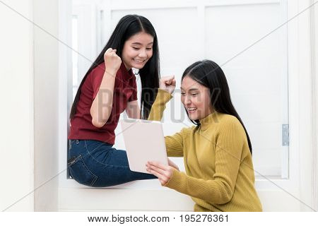 Two Asian university students in an using tablet and glad in unversity. Successful education concept.