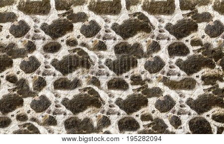 Textured stone walls built of large rough stones held together by dark lumps of white cement limestone