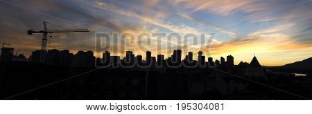 Vancouver Skyline Silhouette with stunning sunset in summertime. A grane symbol of build is on the left