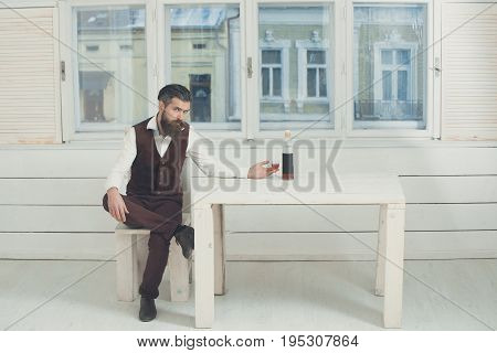 Hipster With Glass And Bottle Of Wine On Table