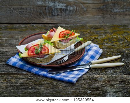 Sandwich with ham, cheese and tomato on plate and on table