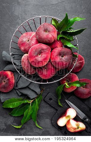 Peaches with leaves on dark background, top view