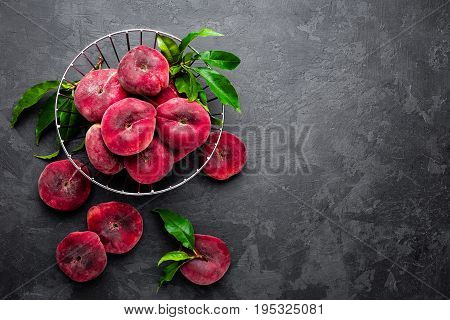 Peaches with leaves on dark background, top view