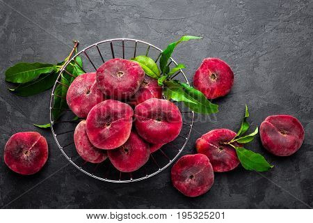 Peaches with leaves on dark background, top view