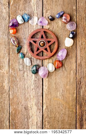 Incense burning in wooden pentagram burner with crystals in heart shape on wooden plank background