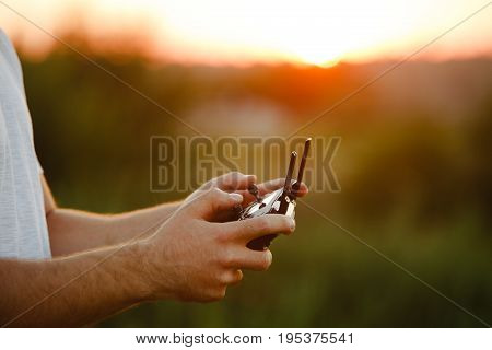 Man holds a drone remote controller in his hands. Close-up of quadcopter RC with antennas during flight. Pilot takes aerial photos and videos with quad