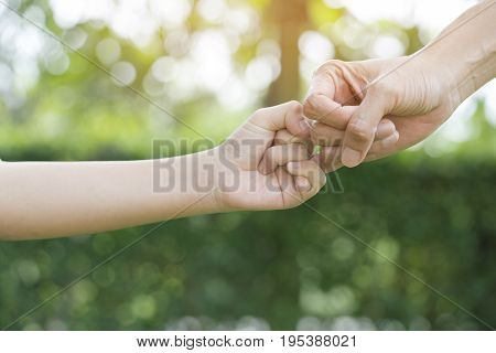 A mother and her child hooking their fingers to make a promise