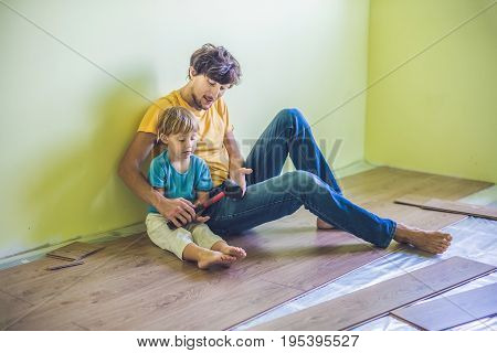 Father And Son Installing New Wooden Laminate Flooring. Infrared Floor Heating System Under Laminate