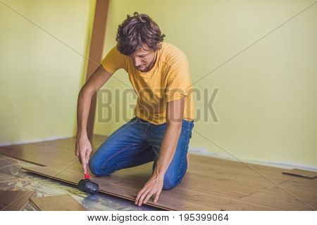 Man Installing New Wooden Laminate Flooring. Infrared Floor Heating System Under Laminate Floor